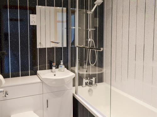 a white bathroom with a sink and a shower at Bay View in Kingsdown