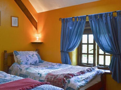 sypialnia z 2 łóżkami i oknem z niebieskimi zasłonami w obiekcie The Bailey w mieście Glasbury