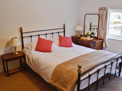 a bedroom with a bed with two red pillows on it at Mill Cottage in Winterborne Steepleton