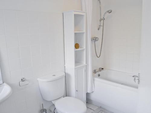 y baño blanco con aseo y ducha. en Mill Cottage, en Winterborne Steepleton