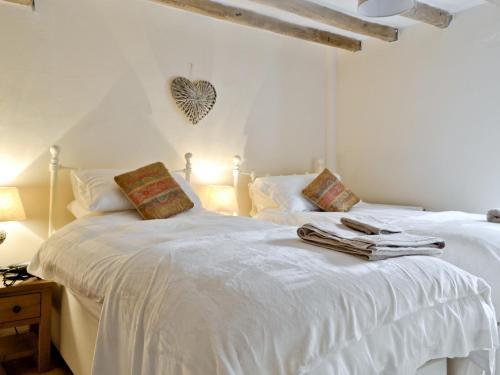 a bedroom with two white beds and a heart on the wall at The Old Sweet Shop in Hook Norton