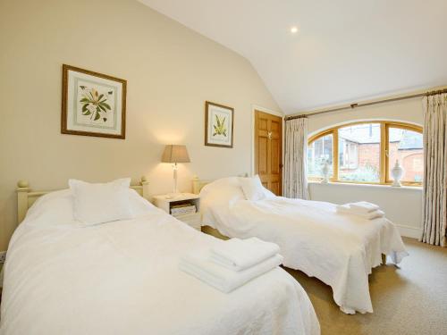 two white beds in a room with a window at The Stables At Weedon Hill Farm in Church Stowe