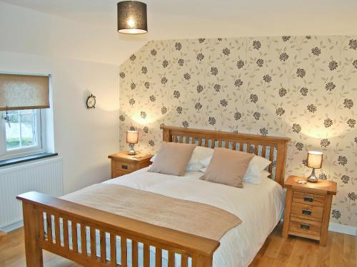 a bedroom with a large bed with two night stands at Home Park Farm Cottages A in Lanteglos