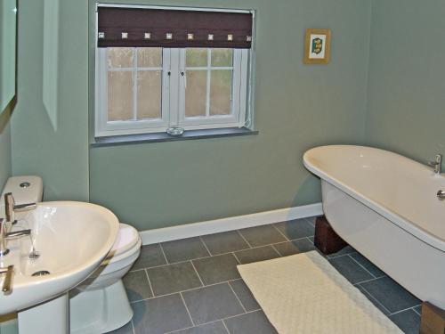 a bathroom with a tub and a toilet and a sink at Home Park Farm Cottages A in Lanteglos