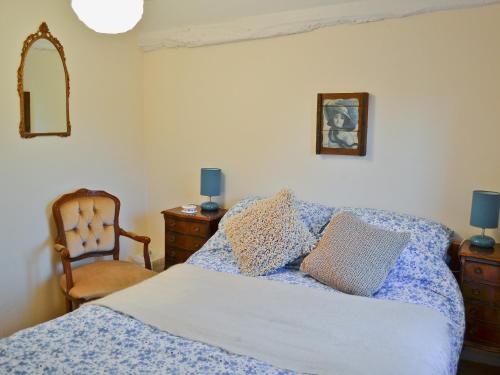a bedroom with a bed and a chair at Rose Cottage in Hythe