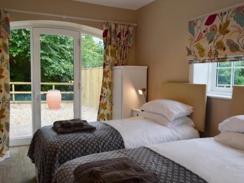 two beds in a room with a window at The Garden Cottage in Rudston