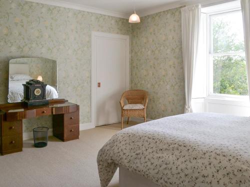 a bedroom with a bed and a mirror and a chair at Burnfoot Of Cluden in Holywood