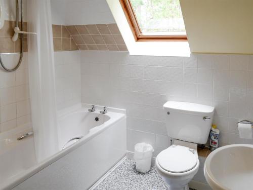 a bathroom with a toilet and a tub and a sink at Rowan Cottage in Glenrossal