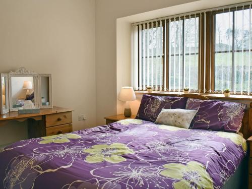 a bedroom with a purple bed and a window at Ty Nant in Llanon