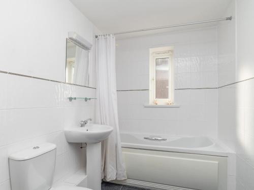 a white bathroom with a sink and a tub and a toilet at 4 Belvedere Court in Paignton