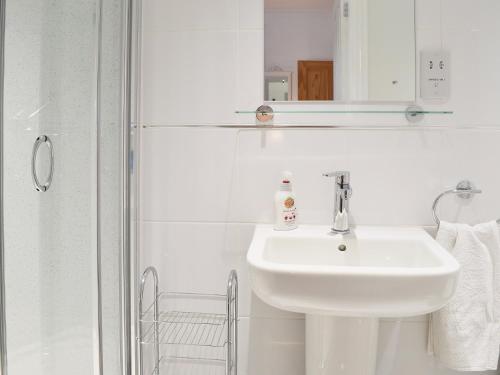 a white bathroom with a sink and a shower at Squirrel Cottage in Windermere