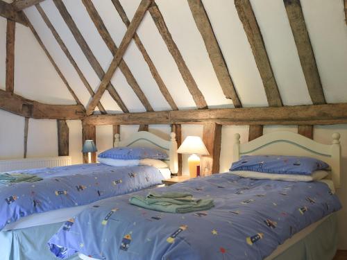 a bedroom with two beds with blue sheets at Bell Corner Cottage in Cratfield
