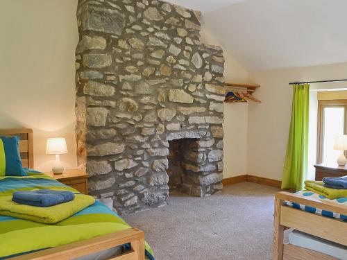 1 dormitorio con 1 cama y chimenea de piedra en Gorsddu, en Llanwrthwl