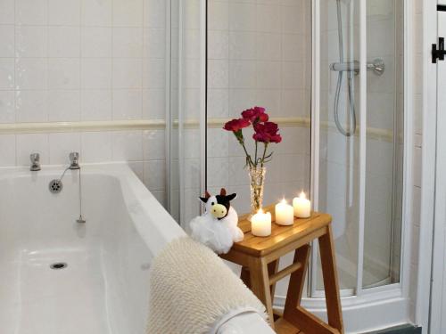 baño con bañera y jarrón de flores y velas en Dairy Cottage en Barnstaple