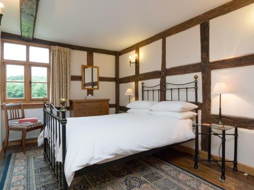 a bedroom with a large bed with white sheets at Brook House in Mathon