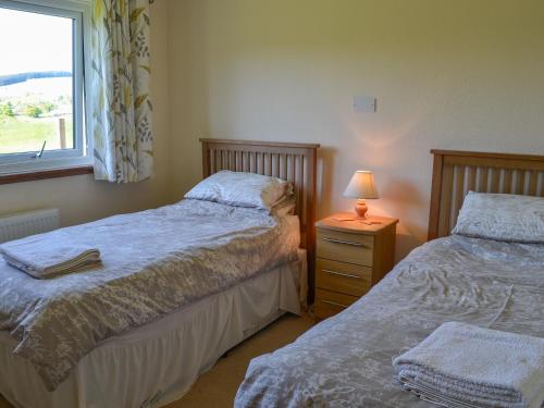 1 dormitorio con 2 camas y mesita de noche con lámpara en Glenbank, en Maxwelton