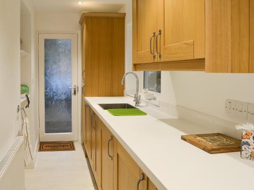 a kitchen with wooden cabinets and a sink at The Coach House in Grasmere