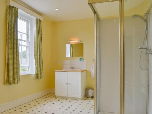 a bathroom with a shower and a sink and a mirror at Cronkhill Farmhouse in Wroxeter