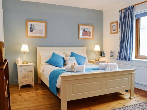 a bedroom with a bed with blue and white pillows at Draigs Cottage in Abergavenny