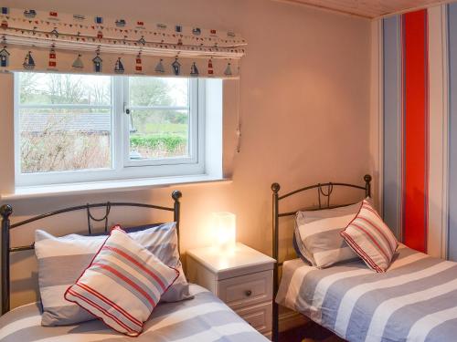 two beds in a room with a window at The Cottage in Penrhos-Lligwy