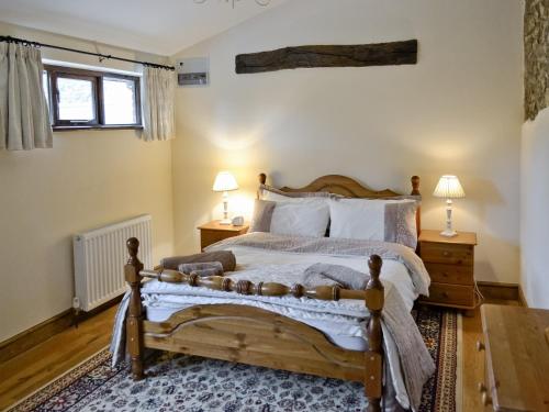 a bedroom with a wooden bed with two lamps and two tables at Horseshoes - E5369 in West Buckland