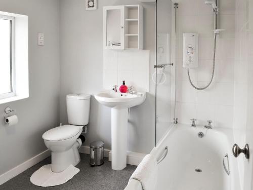 a white bathroom with a toilet and a sink at Eventide in Biggleswade