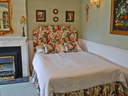 a bed with a floral headboard in a bedroom at The Coach House in Great Easton