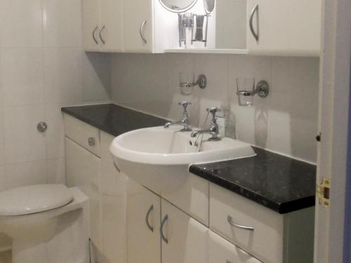 a white bathroom with a sink and a toilet at The Coach House in Great Easton