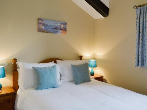 a bedroom with a bed with white sheets and blue lamps at The Hayloft in Kingsbridge
