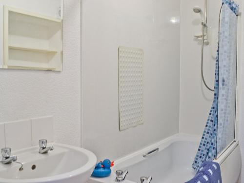 a white bathroom with a sink and a bath tub at Burnbank in Kirkgunzeon