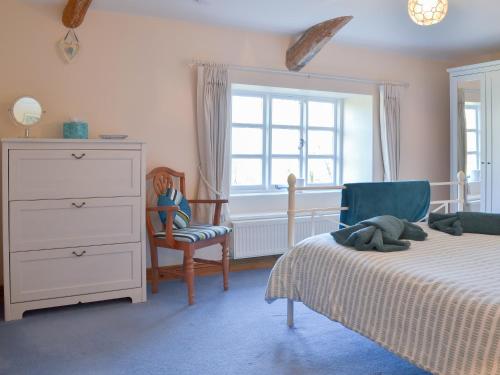 a bedroom with two beds and a dresser and a window at Barton Cottage in North Petherwin