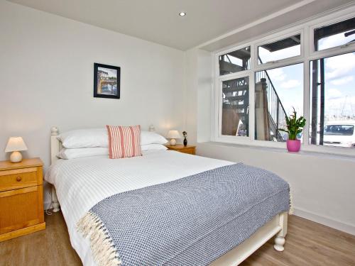 a white bedroom with a bed and a window at Below Decks in Turnchapel