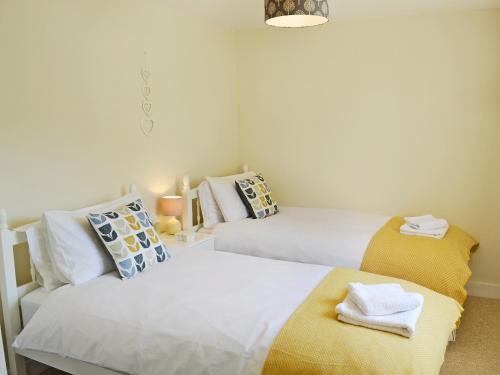 een slaapkamer met 2 bedden met gele en witte kussens bij Acorn Cottage - Ukc1812 in South Perrott