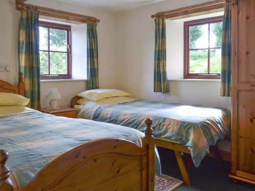 two beds in a bedroom with two windows at The Byre in Morland