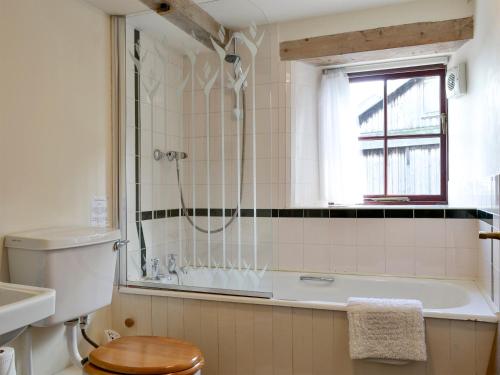 a bathroom with a tub and a toilet and a window at The Byre in Morland