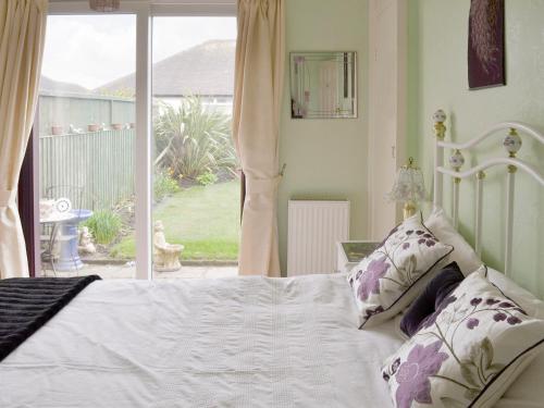 a bedroom with a white bed and a large window at Rossall Beach Cottage in Cleveleys