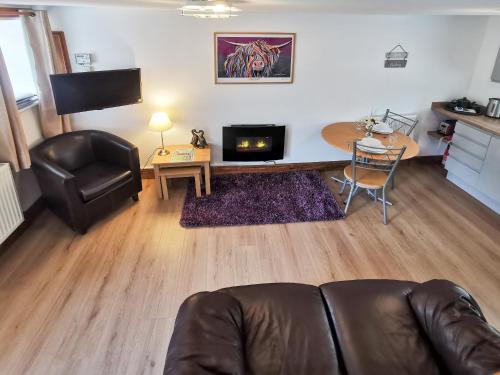 sala de estar con sofá de cuero y mesa en The Calf Shed, en Alston