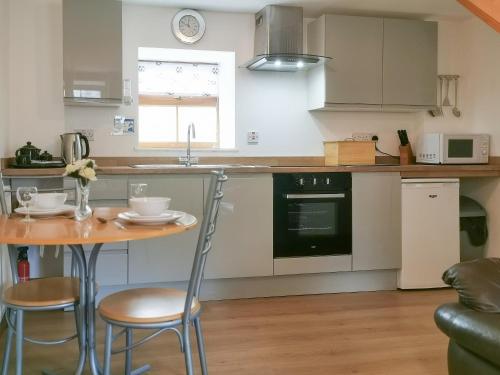 uma cozinha com uma mesa e cadeiras e um lavatório em The Calf Shed em Alston