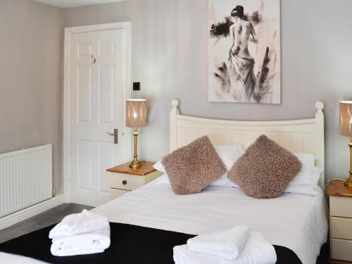 a bedroom with a white bed with two towels on it at Brewers Cottage in Cropton