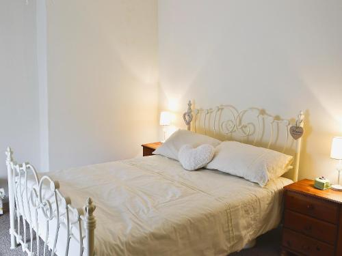 a bedroom with a white bed with two pillows at Jug And Glass Cottage in Upper Langwith