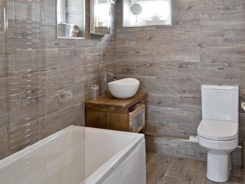 a bathroom with a tub and a toilet and a sink at Willow Tree Cottage in Foxholes