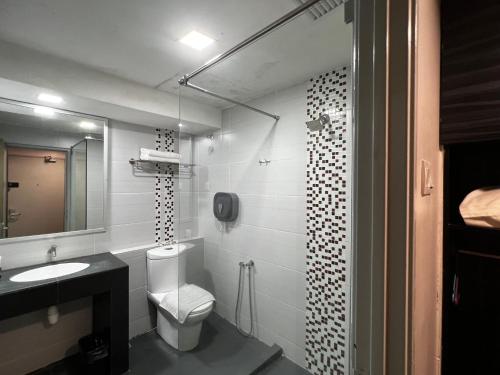 a bathroom with a toilet and a sink and a mirror at Signature Hotel in Kuantan