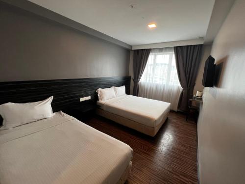 a hotel room with two beds and a window at Signature Hotel in Kuantan