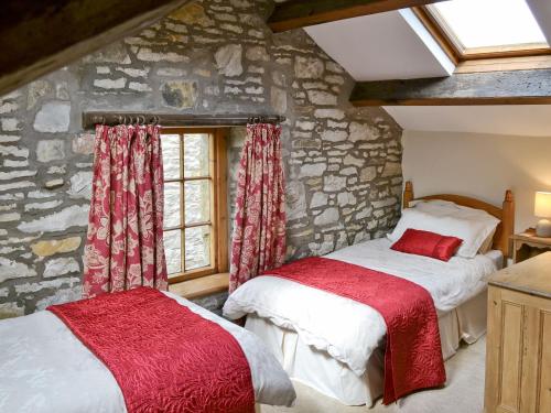 2 camas en una habitación con una pared de piedra en The Corn Mill, en Branthwaite