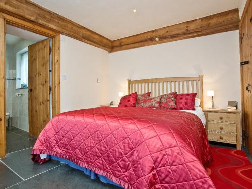 a bedroom with a bed with a red comforter at The Linhay in Little Petherick
