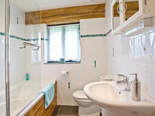 a white bathroom with a sink and a toilet at The Linhay in Little Petherick