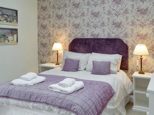 sypialnia z fioletowym łóżkiem i ręcznikami w obiekcie Dray Cottage w mieście East Allington