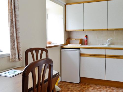 a kitchen with white cabinets and a sink and a dishwasher at Strathspey in Largs