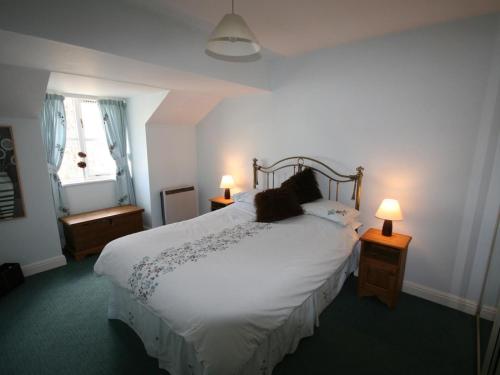 a bedroom with a large white bed with two lamps at College Gate in Windermere