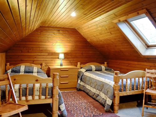a attic bedroom with two beds and a window at Buckhood - Swwy in Pearsie